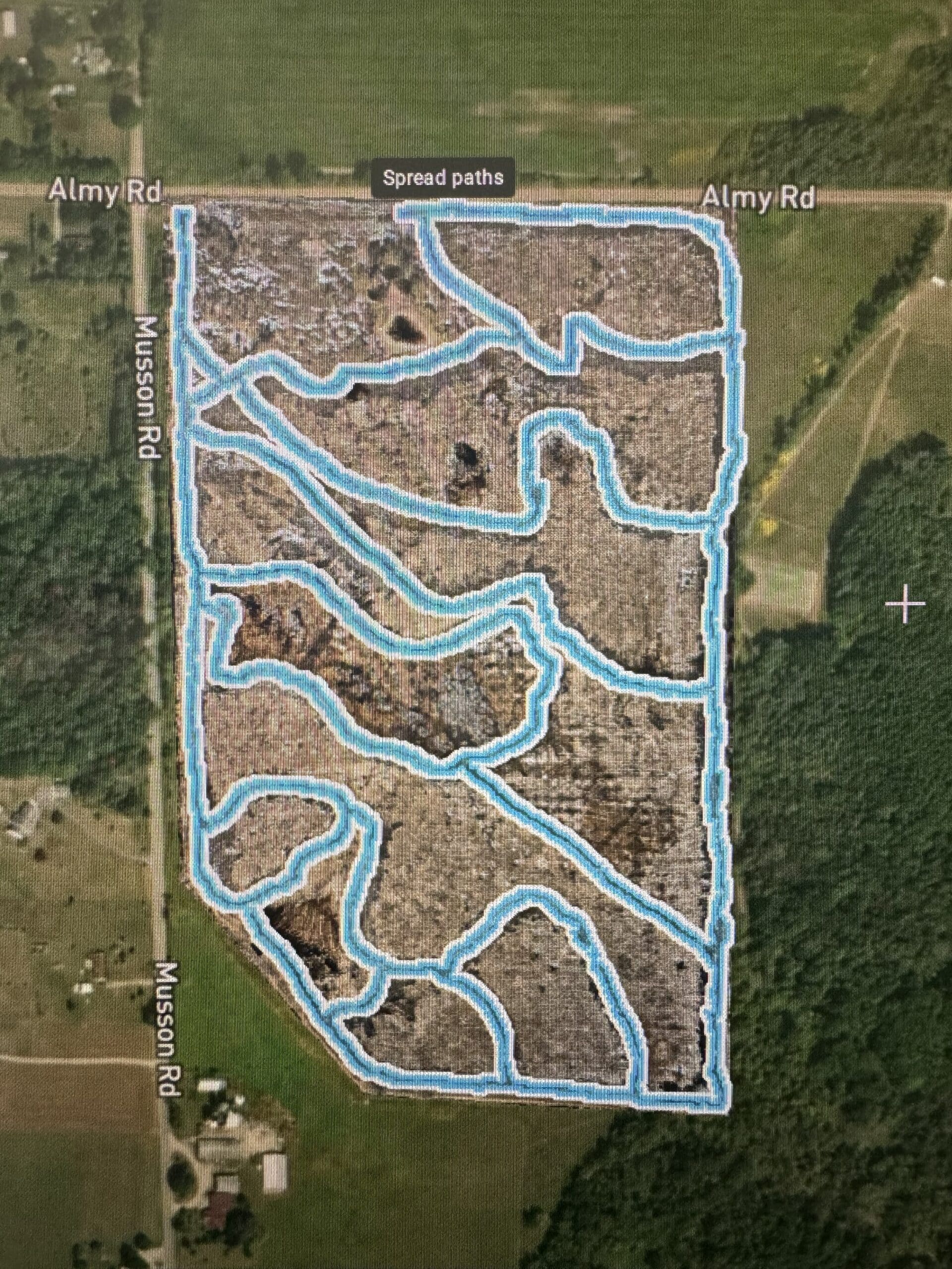 The image shows a drone's planned application paths for a substance across a bounded agricultural area, marked by precise lines against the surrounding landscape.