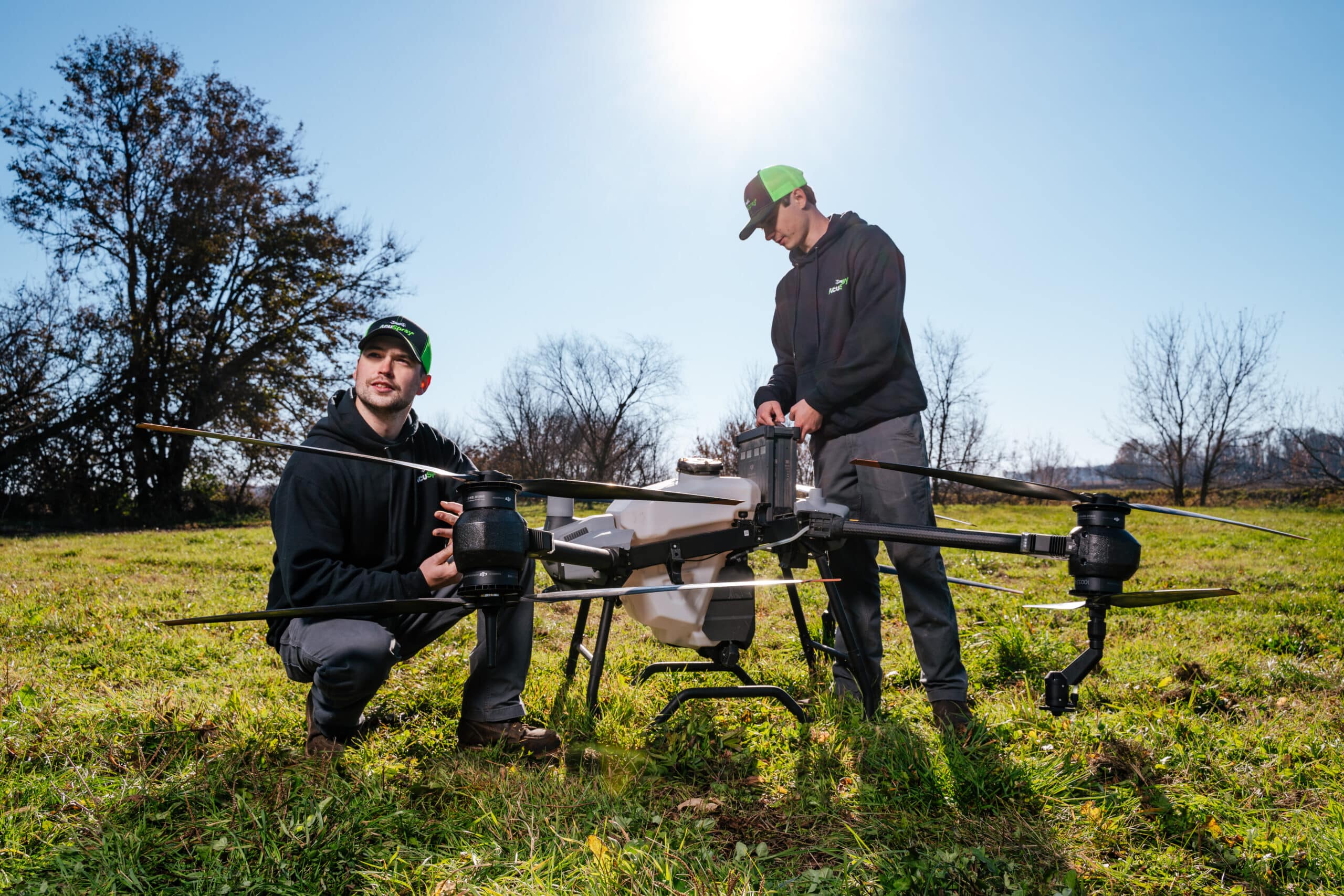 Two technicians prepare an advanced drone for agricultural use in a field at sunrise, highlighting modern farming technology and collaboration.