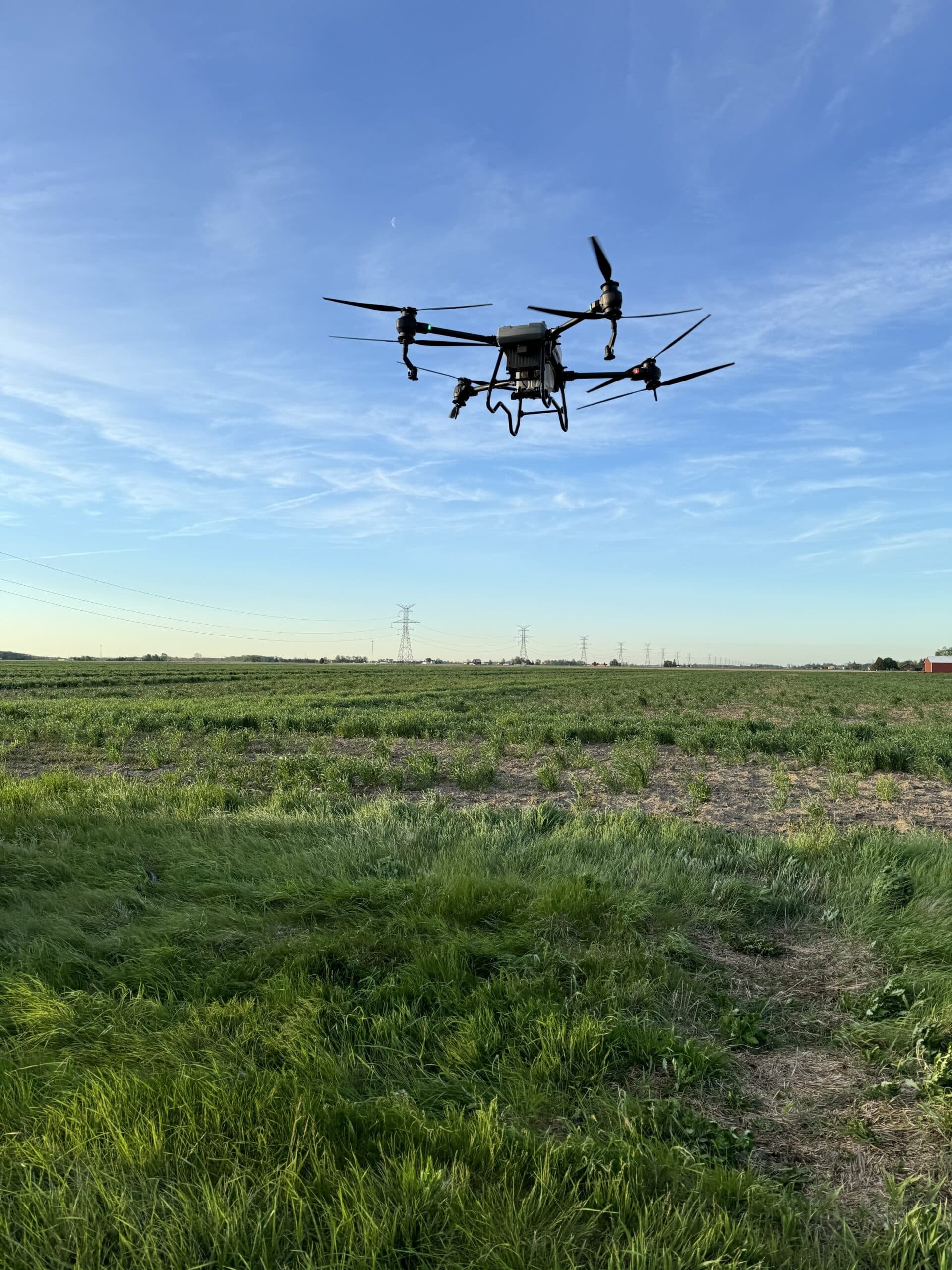 A drone flying over a large grassy field, showcasing its use in precision turf management for accurate application and monitoring.
